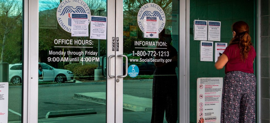 A woman reads notices on the door of a Social Security office in Burbank, Calif. in November 2020.