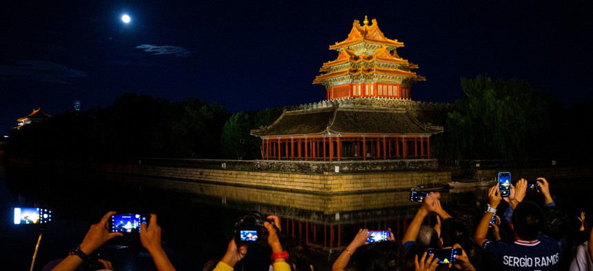 People take photos of the moon and a historic tower near the Forbidden city during the mid-autumn festival in Beijing on Sept. 10, 2022.