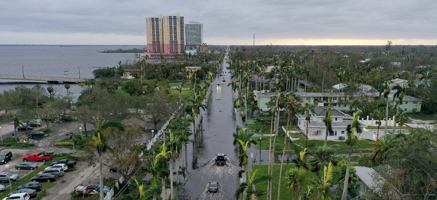 Vehicles make their way through flooded streets in the aftermath of Hurricane Ian in Fort Myers, Fla.