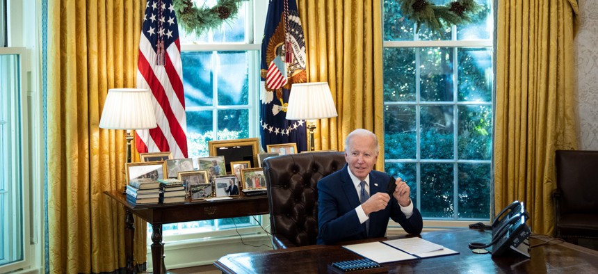 President Joe Biden signs an executive order related to government services in the Oval Office of the White House Dec. 13, 2021.