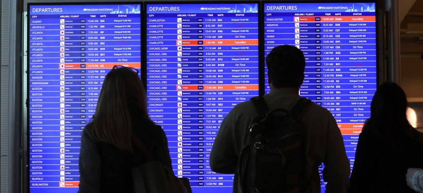 Travelers look at a flight information board at Ronald Reagan Washington National Airport on Jan. 11, 2023. Flights are resuming after an overnight outage of a key FAA system.